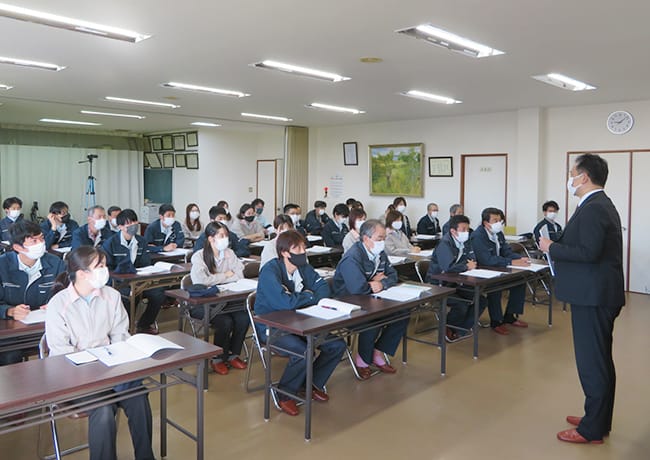 会議室で多くの社員が着席し、講師の話を聞いている研修会の様子