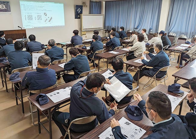 プロジェクター投影資料を見ながら講義を受ける参加者たちの後ろ姿