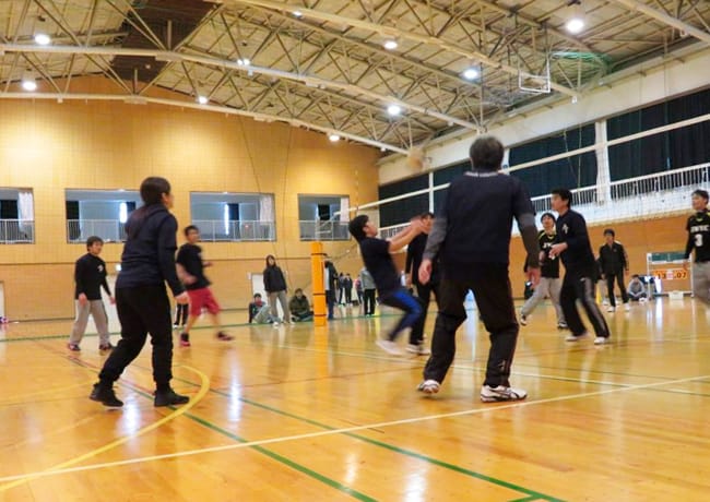 体育館でバレーボールの試合をする参加者たち。チームプレーの様子